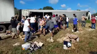 Decenas de personas acudieron al lugar y rapiñaron la mercancía del tráiler volcado, utilizando camionetas y mototaxis para transportar los productos