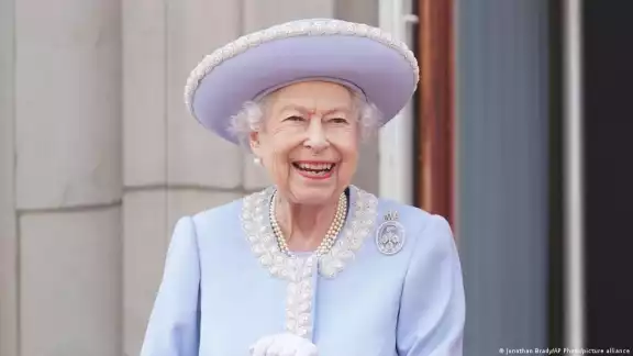Vestida con abrigo y sombrero azul, la monarca se mantuvo sonriente y de pie pero apoyándose en un bastón Vestida con abrigo y sombrero azul, la monarca se mantuvo sonriente y de pie pero apoyándose en un bastón