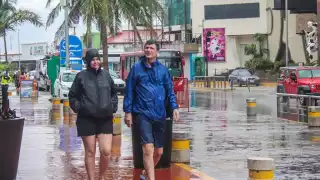 En la Zona Hotelera se observó a grupos de turistas con impermeables y paraguas o entrando a las plazas comerciales