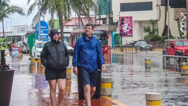 En la Zona Hotelera se observó a grupos de turistas con impermeables y paraguas o entrando a las plazas comerciales