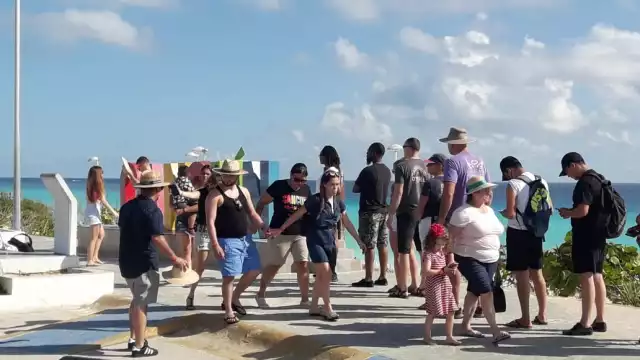 Turistas y locales, en su mayoría sin tapabocas, realizaron una larga fila para tomarse la foto del recuerdo en el parador turístico de Cancún