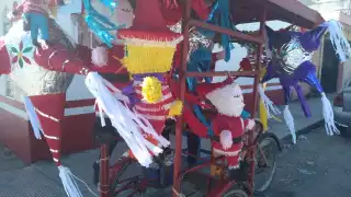 Don Isidro lleva en su triciclo piñatas de todo tipo, desde estrellas hasta a Santa Claus