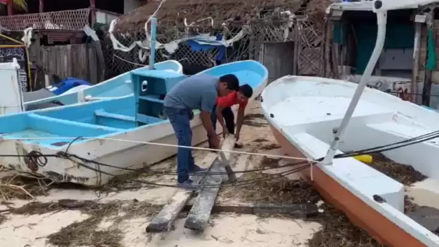 Hombres de mar recuperan sus herramientas que estaban enterradas en la arena. Foto: Karla Cauich.