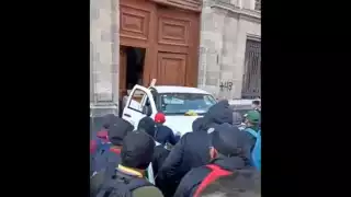 Un grupo de presuntos normalistas de Ayotzinapa derribó con una camioneta de la CFE una de las puertas de Palacio Nacional
