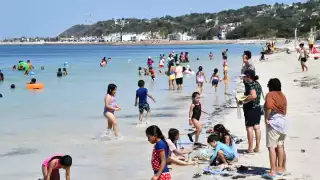 Personas de todas las edades que disfrutaban de la arena, el sol y el mar.