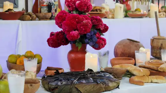 Altar de Hanal Pixán con elementos como el mucbipollo, jícaras, velas y flores. Altar de Hanal Pixán con elementos como el mucbipollo, jícaras, velas y flores.
