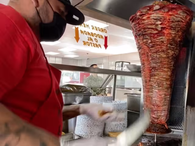Taquero en San Diego prepara una orden de pastor