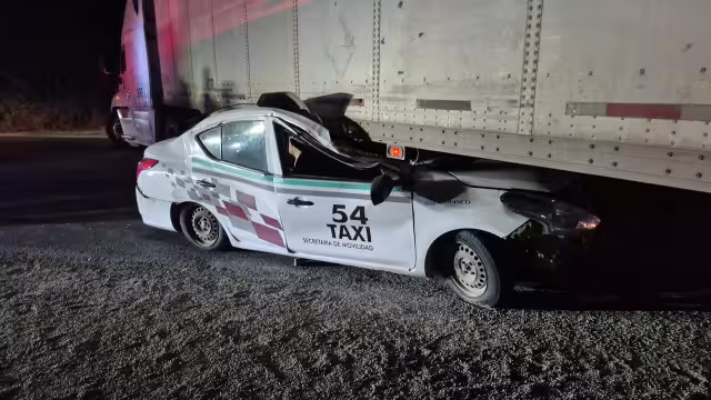 Taxi queda prensado bajo tráiler en carretera federal