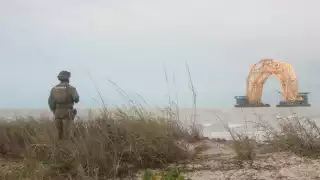 Un elemento de la Semar observa la estructura entre el mar picado