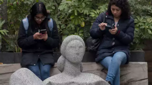 Dos jóvenes en sus teléfonos celulares
