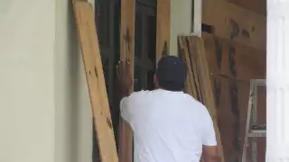 Los empleados de diversos inmuebles se preparan con tablas de madera para proteger puertas y ventanas en Cozumel