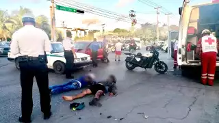 El motociclista y su acompañante terminaron en el pavimento tras el impacto contra el taxi en Cancún, por lo que fueron valorados por paramédicos