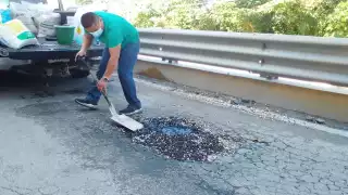 Automovilista molesto tapa bache en el Puente Vial de Playa del Carmen