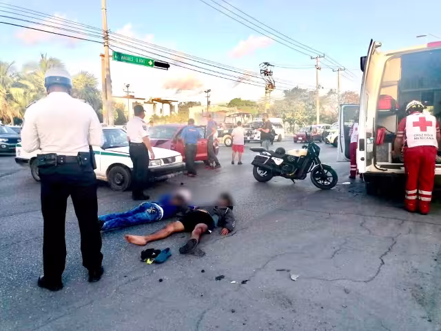 El motociclista y su acompañante terminaron en el pavimento tras el impacto contra el taxi en Cancún, por lo que fueron valorados por paramédicos