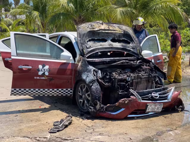 Taxi Nissan Versa se incendia tras salir de una gasolinera. Presunto cortocircuito en el motor habría originado el fuego.