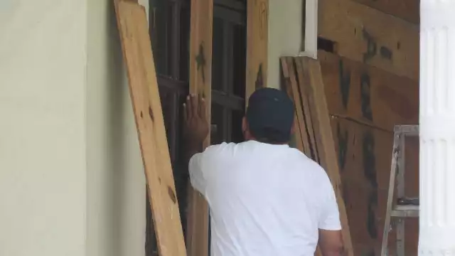 Los empleados de diversos inmuebles se preparan con tablas de madera para proteger puertas y ventanas en Cozumel