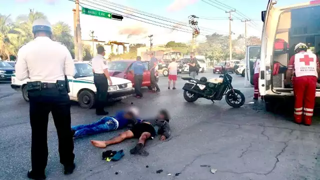 El motociclista y su acompañante terminaron en el pavimento tras el impacto contra el taxi en Cancún, por lo que fueron valorados por paramédicos