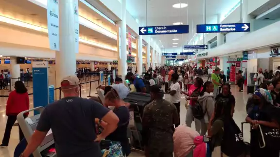 Algunos turistas descienden de sus vehículos de transporte para caminar y no perder sus vuelos en Cancún Algunos turistas descienden de sus vehículos de transporte para caminar y no perder sus vuelos en Cancún