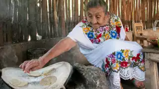 Sentada en un banquillo junto a su fogón, la abuelita de Maní es feliz elaborando sus platillos de la gastronomía yucateca