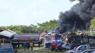 Bomberos tratan de sofocar el incendio en un depósito de carros chatarra