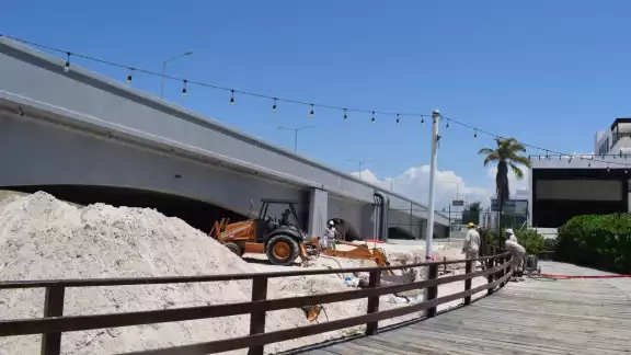 Visitantes observaron una excavadora y una cuadrilla de trabajadores junto al andador de madera de Progreso Visitantes observaron una excavadora y una cuadrilla de trabajadores junto al andador de madera de Progreso