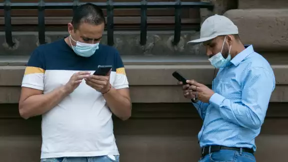 Dos hombres revisan sus teléfonos celulares
