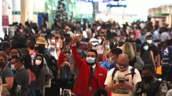 Algunos de los viajeros se les observa sentados en el piso, esperando poder pasar al aérea de check in Algunos de los viajeros se les observa sentados en el piso, esperando poder pasar al aérea de check in