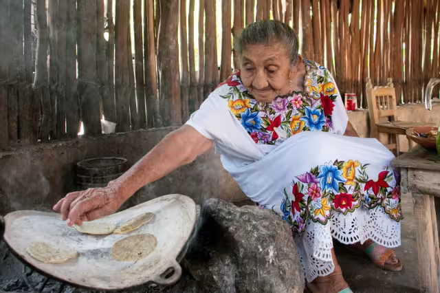 Sentada en un banquillo junto a su fogón, la abuelita de Maní es feliz elaborando sus platillos de la gastronomía yucateca