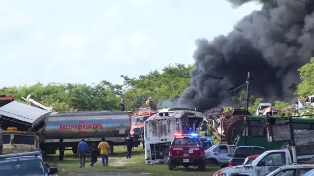 Bomberos tratan de sofocar el incendio en un depósito de carros chatarra