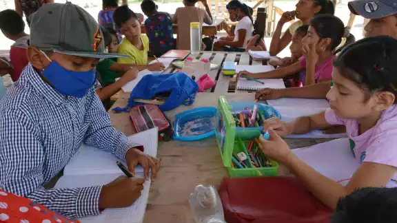 En un tinglado y con improvisado mobiliario escolar, las maestras realizan su labor