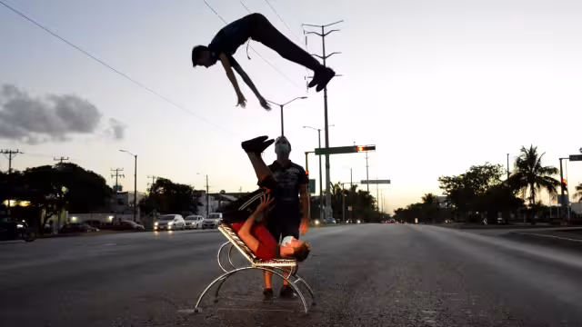 Los dos jóvenes realizan malabares al aire, quienes son supervisados por su padre