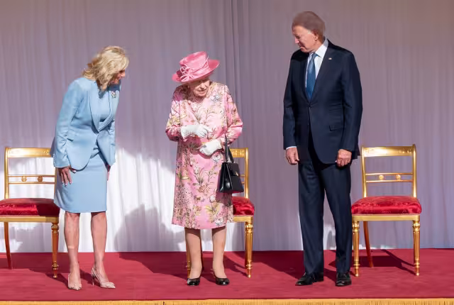 Con traje floreado y sombrero rosados, la soberana de 95 años, enmarcada  por Joe Biden y su esposa Jill, asistió a un desfile de guardias de honor