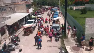 Una larga fila se forma afuera de la escuela normal de personas que fueron por su pedazo de carne robada