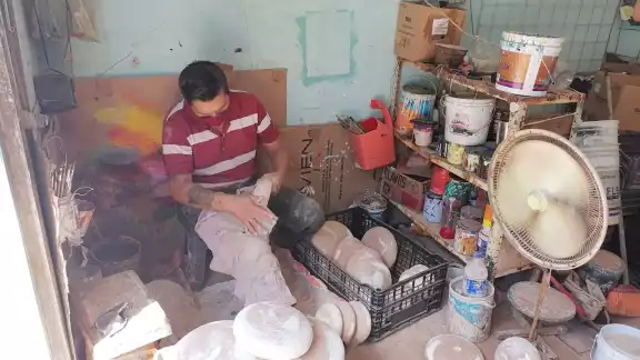 Exhibe las piezas de barro al frente de su pequeño negocio Exhibe las piezas de barro al frente de su pequeño negocio