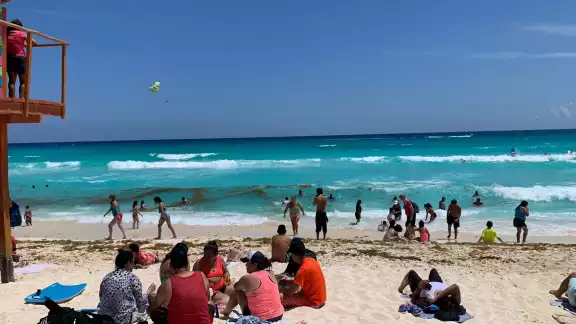 Familias enteras disfrutan del agua color turquesa de la playa Familias enteras disfrutan del agua color turquesa de la playa