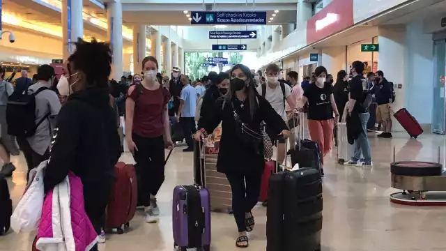 La aglomeración de pasajeros en las terminales del aeropuerto de Cancún esperan la salida de sus vuelos sin atrasos