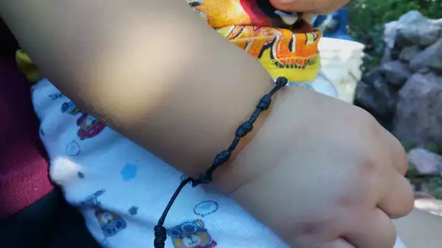 Es una tradición de Día de Muertos elaborar pulseras de hilo negro para proteger a los infantes