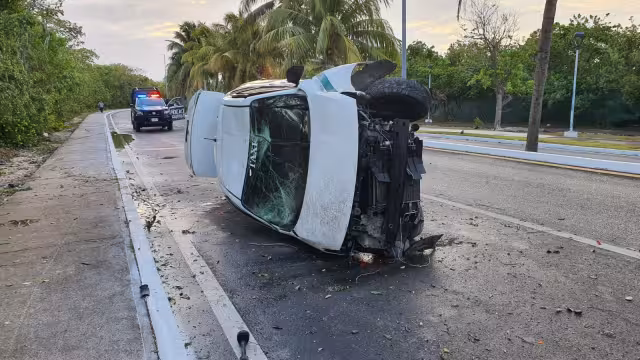 El taxi quedó volcado sobre su lado derecho en la Zona Hotelera de Cancún, hasta la llegada de una grúa, que luego lo remolcó fuera de la vía