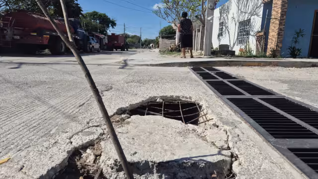 Vecinos reportan daños a vehículos por el hundimiento en la calle.