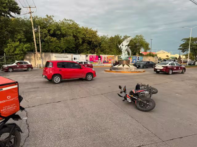 Moto de plataforma de reparto impacta contra auto en la glorieta de los Delfines; sin lesionados