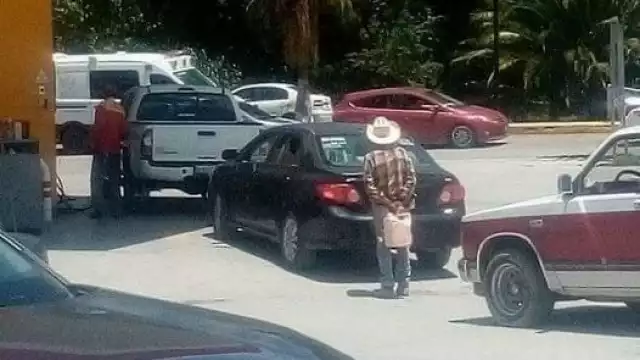A pesar del sol, el hombre esperaba su turno tras dos autos que cargaban gasolina