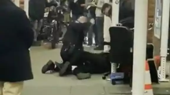 Momento en que el oficial ataca al indigente en el suelo Momento en que el oficial ataca al indigente en el suelo