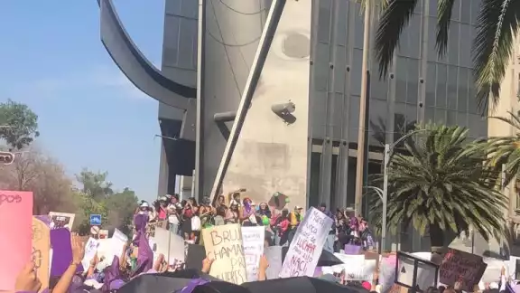 Mujeres reunidas con carteles y sus pañuelos morados Mujeres reunidas con carteles y sus pañuelos morados