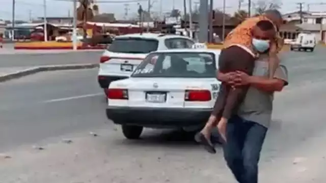 Un hombre carga a su mamá para llevarla a vacunar contra el COVID-19