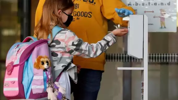 Niña tomando una porción de gel sanitario Niña tomando una porción de gel sanitario
