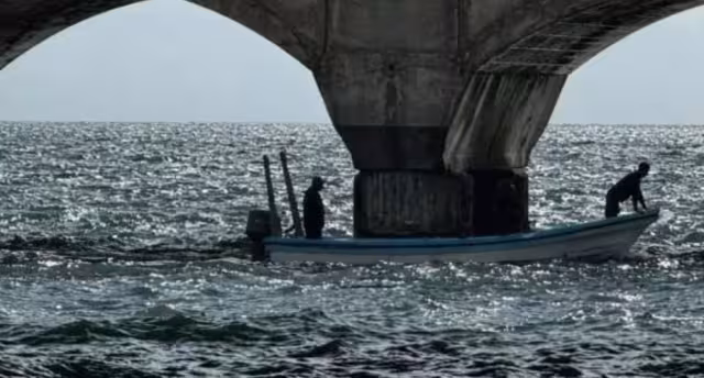 Trabajadores de Pemex colocan barreras junto al muelle para contener manchas de combustible