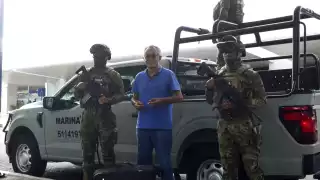 Elementos de la Marina ayudan a pareja de turistas a abrir su maleta en el aeropuerto de Cancún