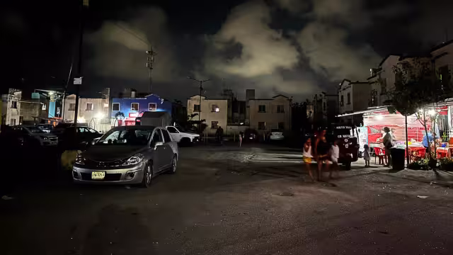 Mientras las luminarias brillan por su ausencia, los vendedores de comida y automóviles brindan un poco de luz a los transeúntes, en Villas Otoch Paraíso.