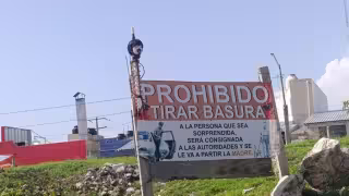 Singular letrero con cabeza advierte: “Prohibido tirar basura”