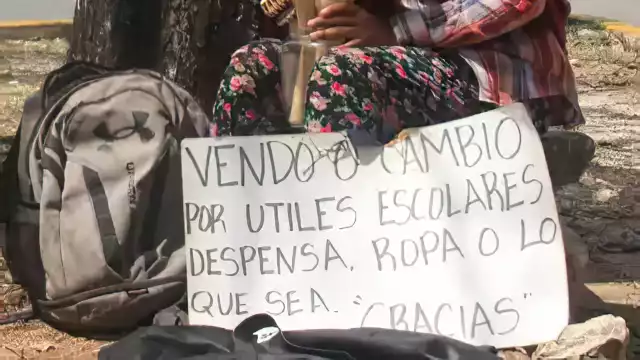 La pequeña sostiene un cartel con la esperanza de vender los utensilios